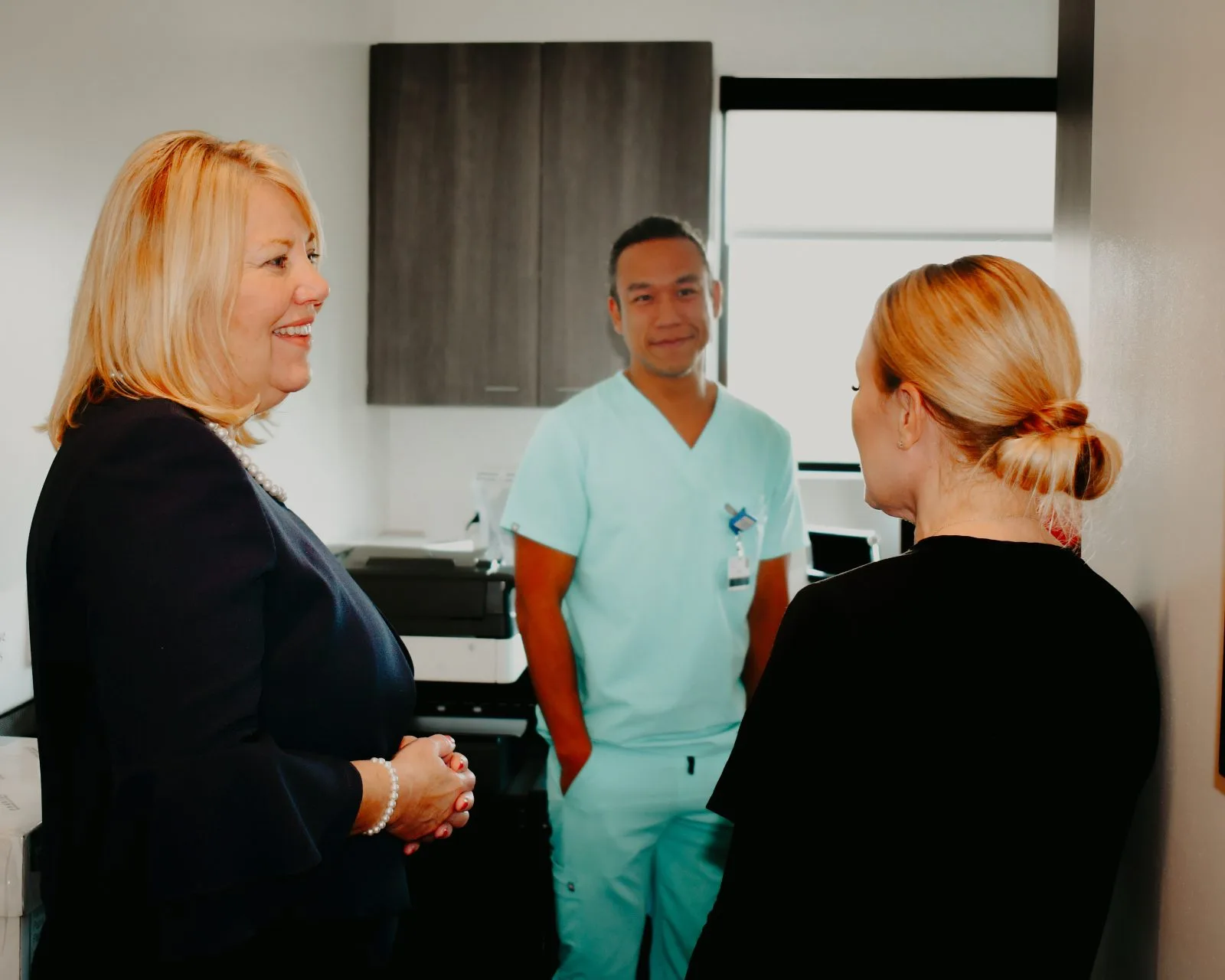Regency Specialties provider in teal scrubs consulting with two patients in a clinical examination room